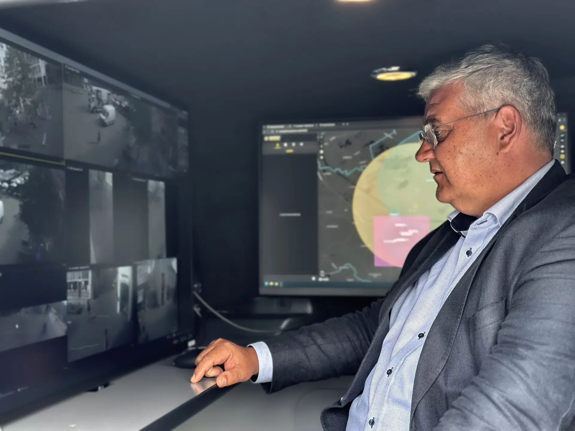Burgemeester kijkt naar camerabeelden in mobiel commandocentrum