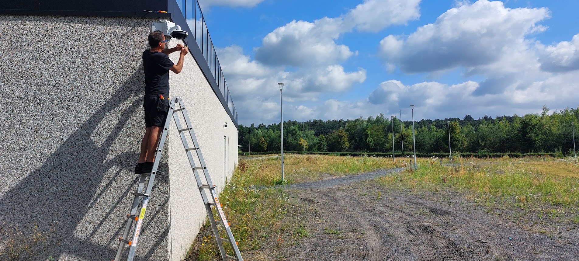 Man op ladder installeert camera